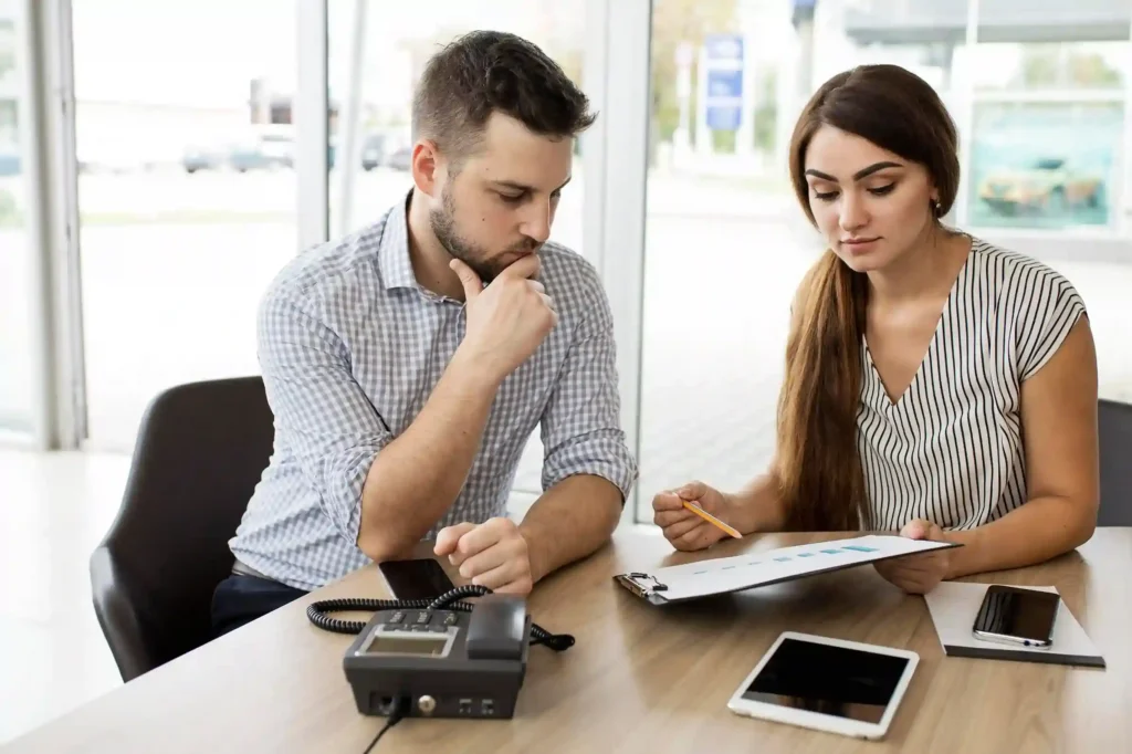 Healthcare revenue cycle management meeting: A focused male medical billing expert listens to a female doctor discuss her EHR software and billing concerns in a modern office setting.
